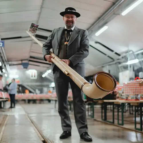 alphorn Ein Mann im Trachtanzug haelt ein Alphorn